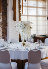 banquet round tables, decorated with a bouquet of white flowers in the center of the tables
