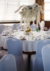 banquet round tables, decorated with a bouquet of white flowers in the center of the tables