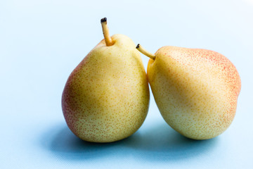 Two ripe sweet organic pears on blue background. Vegan diet fruits.