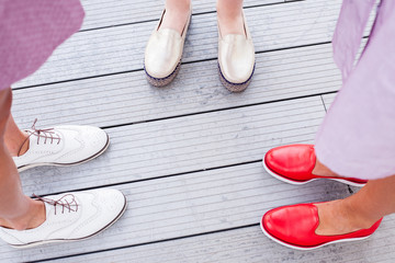 Freands story told by boots. Three girls in colorful shoes standing on floor. Feet and shoes. Selfie image taken from above.