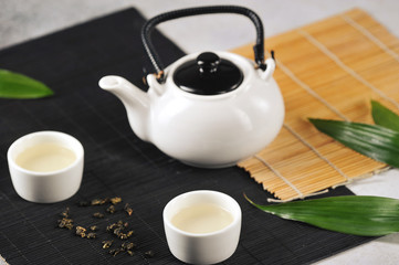 Two white cups of green tea and a teapot on bamboo napkins. Tea ceremony concept. 