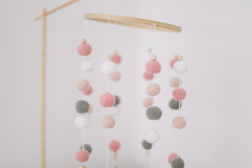 Details of newborn baby room. Toys above the baby crib. Hanging carousel of soft colorful balls for the child.