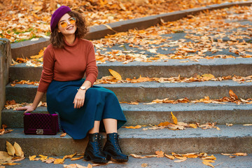 Outdoor autumn portrait of happy smiling lady wearing wrist watch,  beret, orange glasses,...