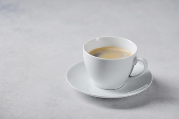 Coffee in a white cup on a light background. Free space for text.