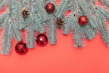 Obraz na płótnie Canvas Creative flat lay overhead Christmas composition with fir tree branches, cones and bright ballsvon red background with copy space for your text Minimalism style composition.