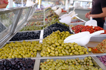 Various marinated olives for sale in a market window.
