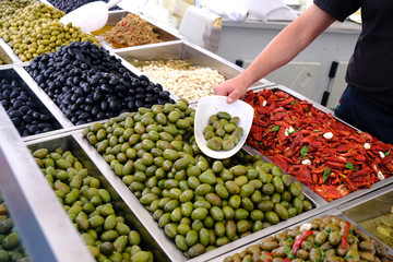 Various marinated olives for sale in a market window.