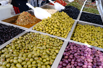 Various marinated olives for sale in a market window.