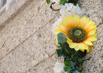 Arranjo de flores artificiais pendurados numa parede em pedra