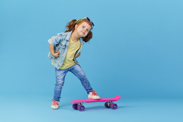 Stylish cool little girl child with skateboard over blue background