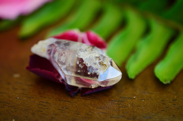 Clear quartz point on wood table in natural lighting. Woman's hand - High Quality Clear Quartz...