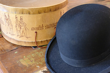 A historic hatbox from Berlin in the 19th century with a bowler on an old wooden table. seit is...