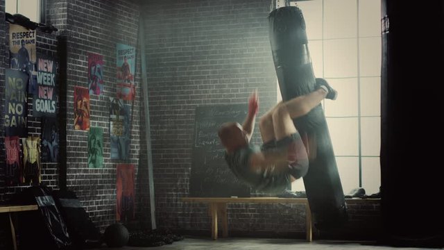 Punching Bag Crunches. Strong Masculine Man Embrassing the Bag with His Legs and Pumping His Abs and Core Muscles. Handsome Male Trains in a Gym and Falls in the End. Sport Accident Causing Back Pain.