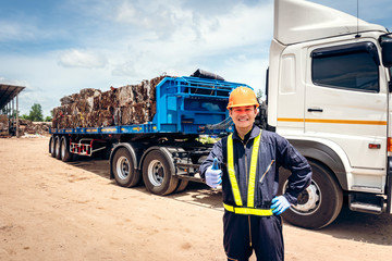 A photograph of an engineer standing with a thumbs up in the background of a truck in the recycling...
