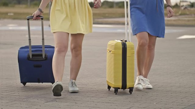 Passengers with suitcases walking on the platform of the railway station. Two women with luggage going on the airport