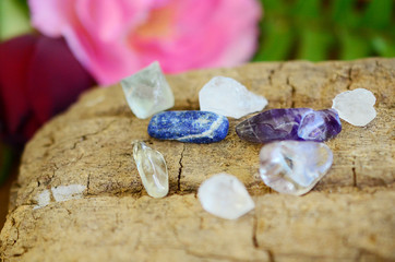  Clear Quartz, Lapis Lazuli, Fluorite, Amethyst and Iris Quartz. Collection of small healing crystals. Bright colors on wooden background. Purple, blue and white crystal variety. 