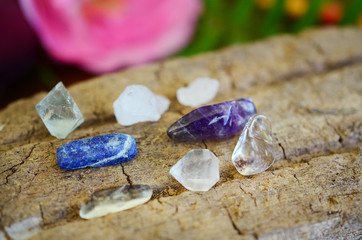  Clear Quartz, Lapis Lazuli, Fluorite, Amethyst and Iris Quartz. Collection of small healing crystals. Bright colors on wooden background. Purple, blue and white crystal variety. 
