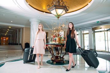Young girls near reception desk in hotel. Young girls comes to the hotel.