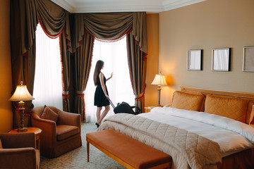 Young women with suitcase are staying in a hotel room.