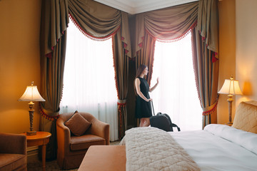 Young women with suitcase are staying in a hotel room.