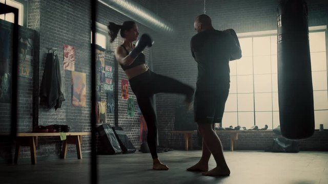Fit Athletic Woman Kickboxer Punches the Punching Pads During a Workout in Gym. She's Beautiful and Energetic. Strong Partner is Holding the Boxing Pads. Intense Self-Defence Training.