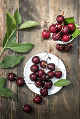 cherry berries in raindrops lie in a saucer on a wooden table