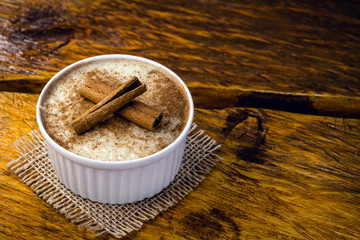 Typical sweet of Brazil in June and July parties. Sweet rice porridge with cinnamon in a bowl on a background.