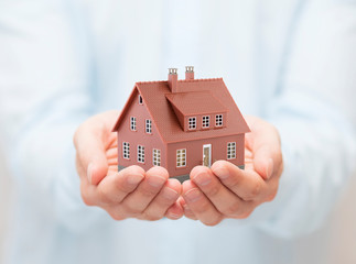 Small brown toy house in hands 