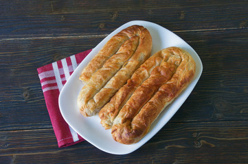 Balkan cuisine. Two bureks - popular national dish - on white plate.  Flat lay, dark rustic background