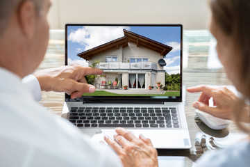 Businesspeople Looking At House On Laptop