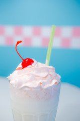 Glass of milkshake with whipped cream and cherry