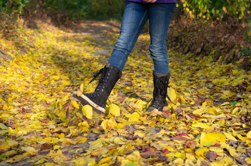 A man walking on yellow foliage. Autumn in the park. Feet and leaves.