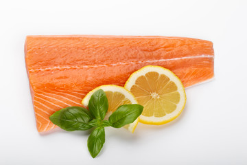 Fresh raw salmon fillets with herbs and lemon isolated on white background.