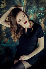 Portrait of young beutiful girl with brown curly hair, weared in black dress,stylish makeup. Studio shot