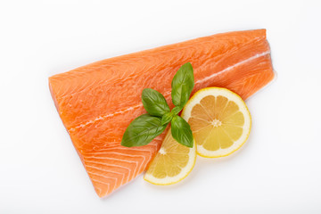 Fresh raw salmon fillets with herbs and lemon isolated on white background.