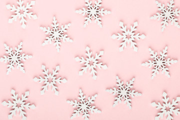 Christmas background. White snow decorations on a pink background.