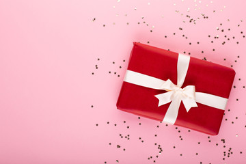 Gift or present box and stars confetti on color table top view. Flat lay composition for birthday, mother day or wedding.