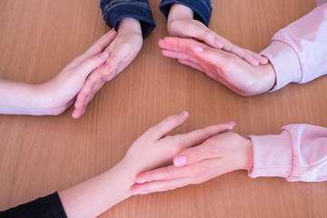 Three pairs of hands of teenage girls on the table close up