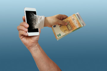 male muscular hand holds a smartphone, a hand with a bundle of euro paper money got out of the...