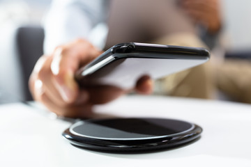 Man Charging Smartphone Using Wireless Charging Pad