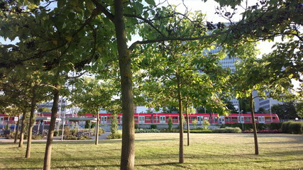 S-Bahn im Bahnhof Eschborn-Süd hinter Freizeitpark Unterwiesen vor Bürogebäude Hochhaus