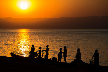 Fototapeta premium Lake Malawi at Monkey Bay, People gathering togehter at the Beach, washing dishes, talking, red sunset, South-East-Africa