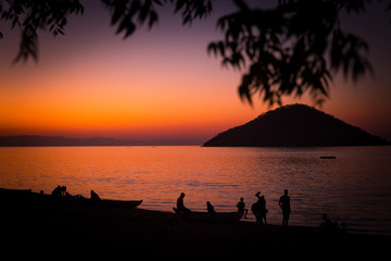 Lake Malawi at Monkey Bay, People gathering togehter at the Beach, washing dishes, talking, red sunset, South-East-Africa