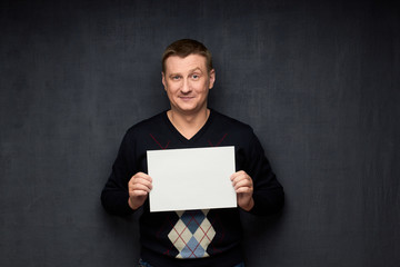 Portrait of satisfied man holding white blank paper sheet