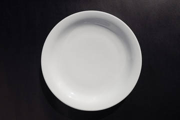 White ceramic round plate on black background