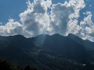 Through the clouds, the rays of the sun break through the mountains. Rosa Khutor