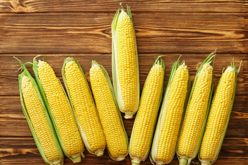 Ripe, sweet, fresh corn on cobs, closeup on a brown rustic wooden table.