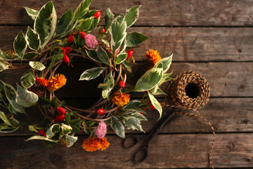 summer wreath with green leaves and rosehip on old wooden background