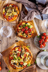 Fresh selfmade mini pizza on rustic wooden oak table 