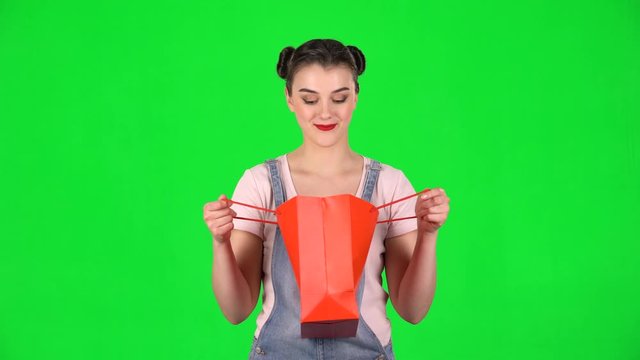 Girl takes out package then looks into it and is very upset on a green screen